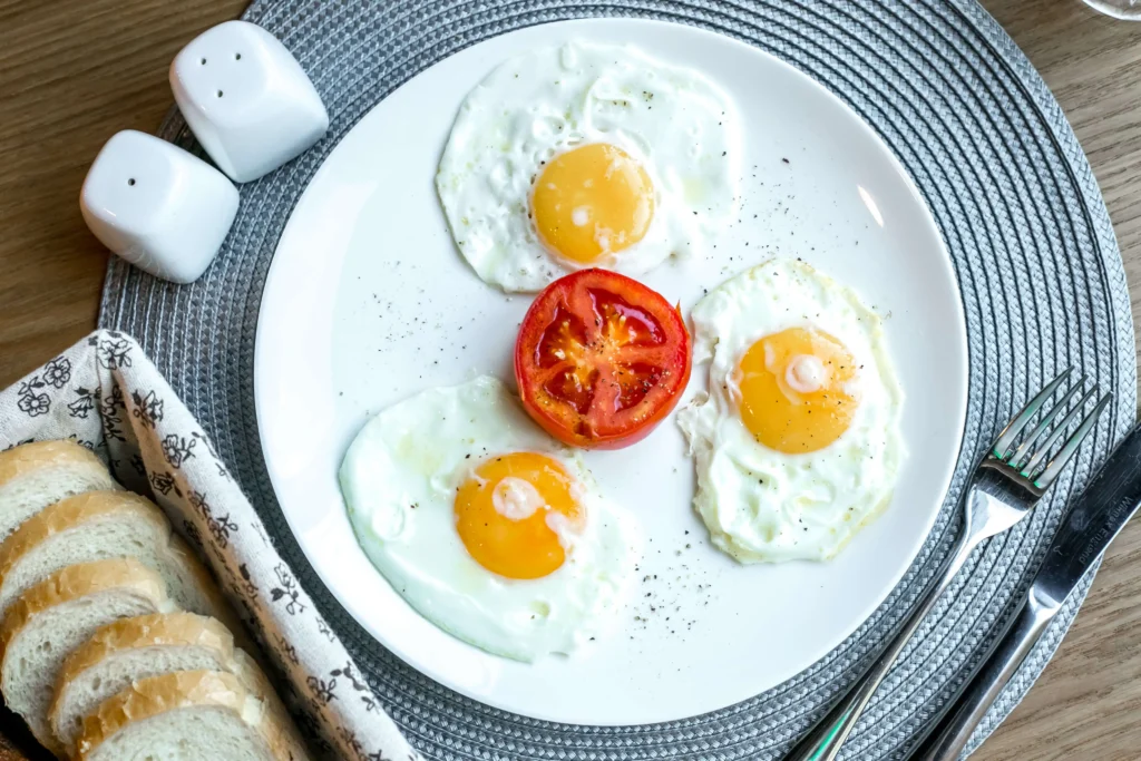 top view fried eggs with tomato plate with salt pepper table